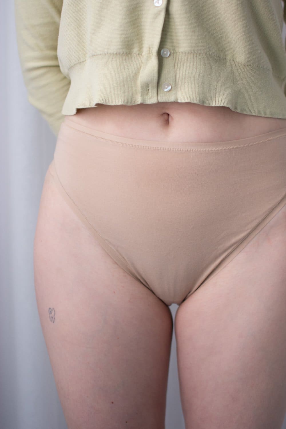 Natori bliss bare cotton high cut brief in cafe, front view on a model, close-up.