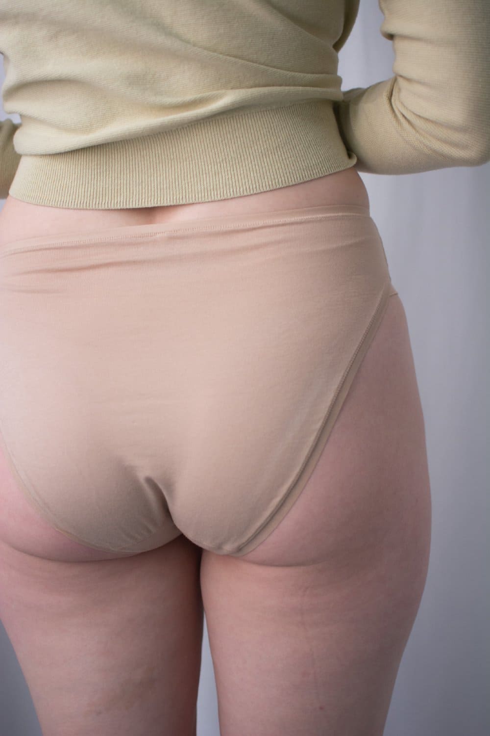 Natori bliss bare cotton high cut brief in cafe, side view on a model, close-up.
