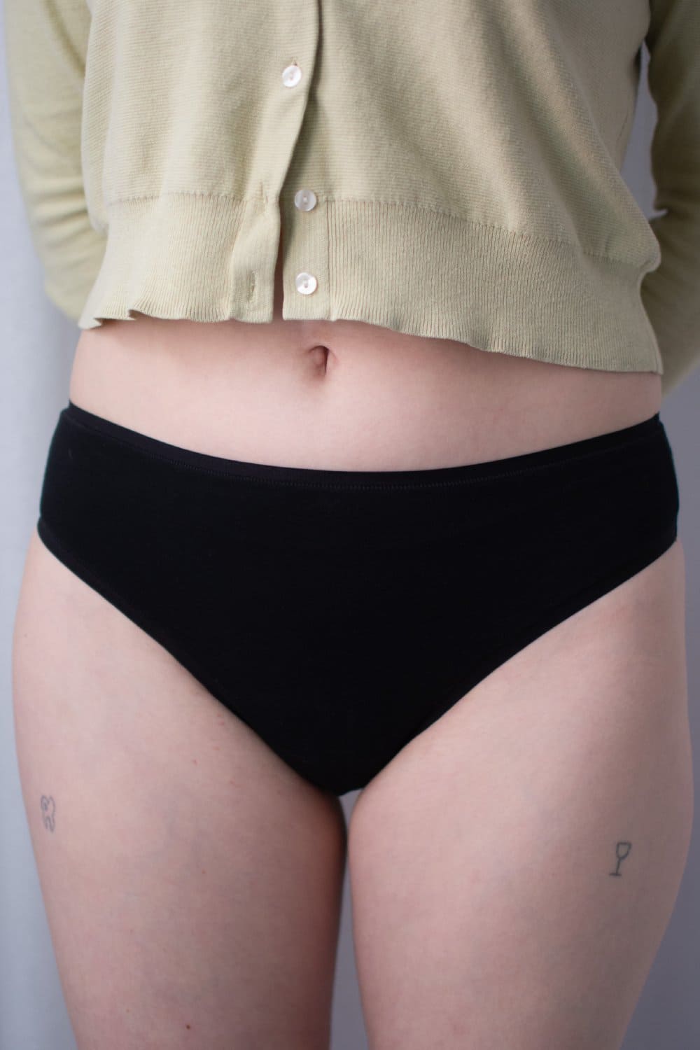 Natori bliss bare cotton thong in black, front view on a model, close-up.
