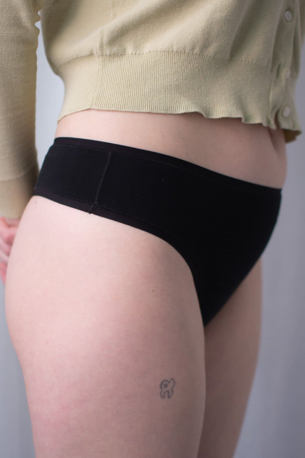 Natori bliss bare cotton thong in black, side view on a model, close-up.