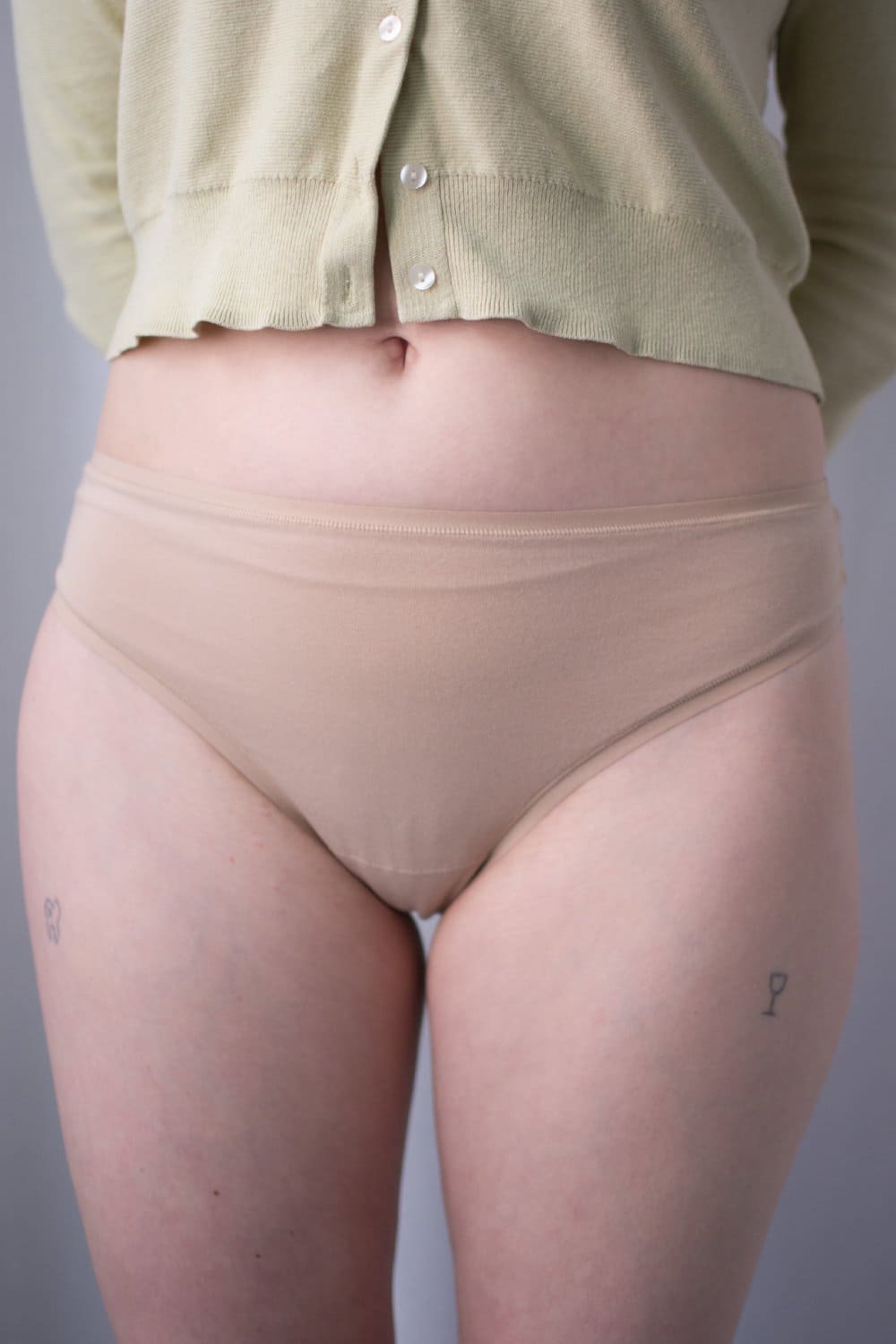 Natori bliss bare cotton thong in cafe, front view on a model, close-up.