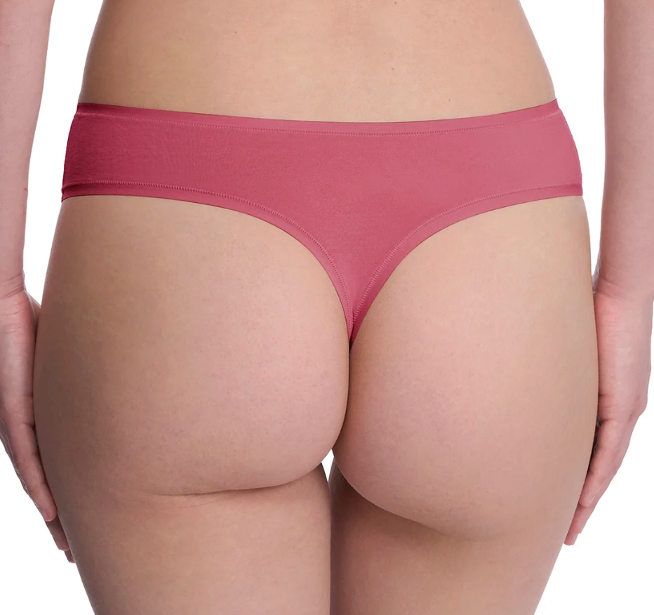 Rear view of a model wearing a dusty rose pink thong-style underwear bottom against a plain white background.