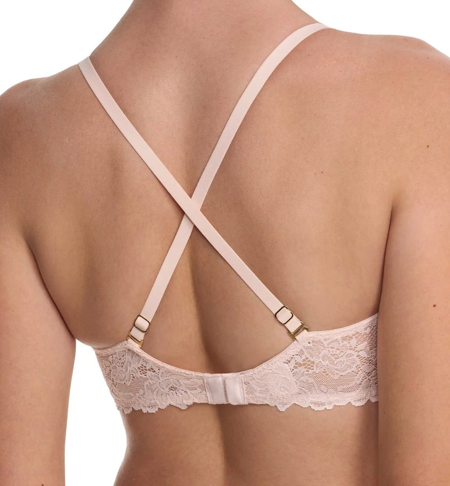 Rear view of a woman wearing a pale blush pink lace bra with crossed back straps and small gold-tone hardware.