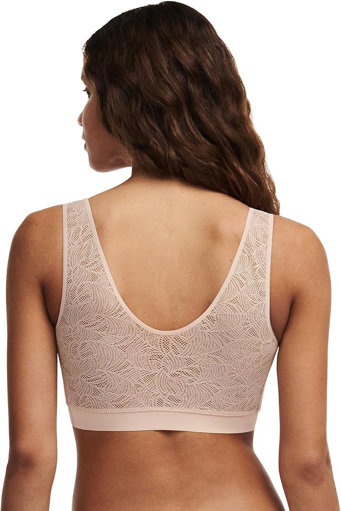 Rear view of a woman wearing a beige lace bralette with a wide underband, shown against a plain white background.