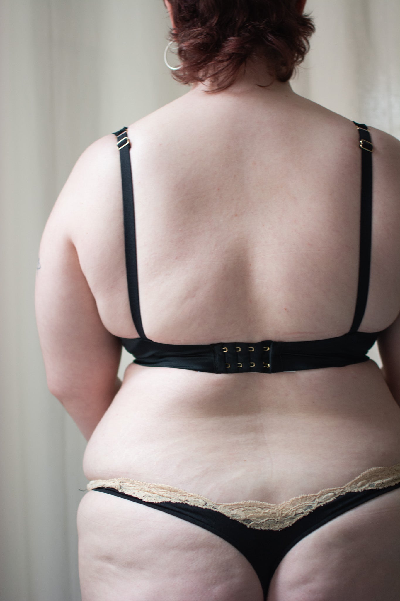 Person wearing black lingerie set against a neutral background.