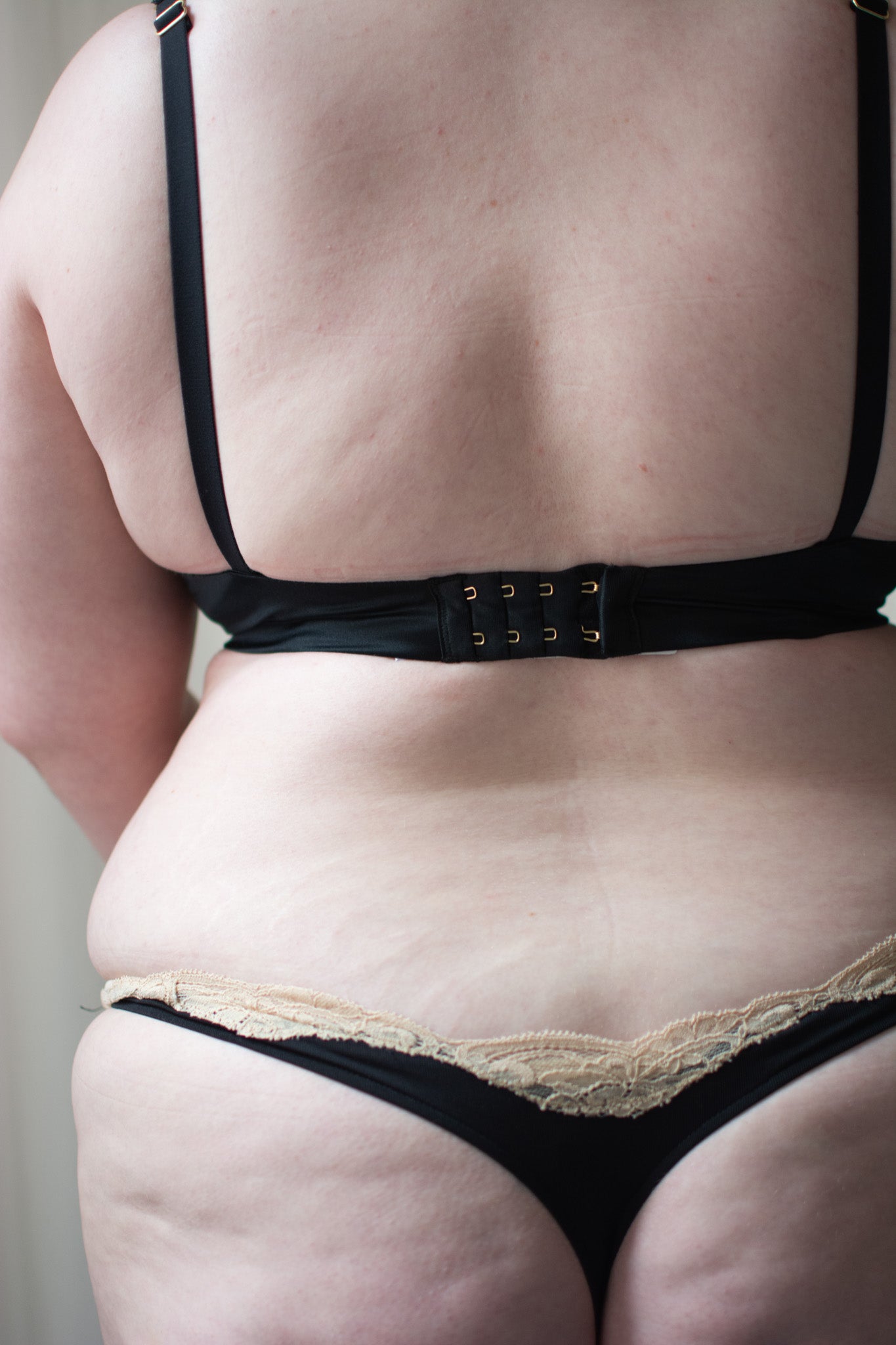 Person wearing black lingerie set against a neutral background.