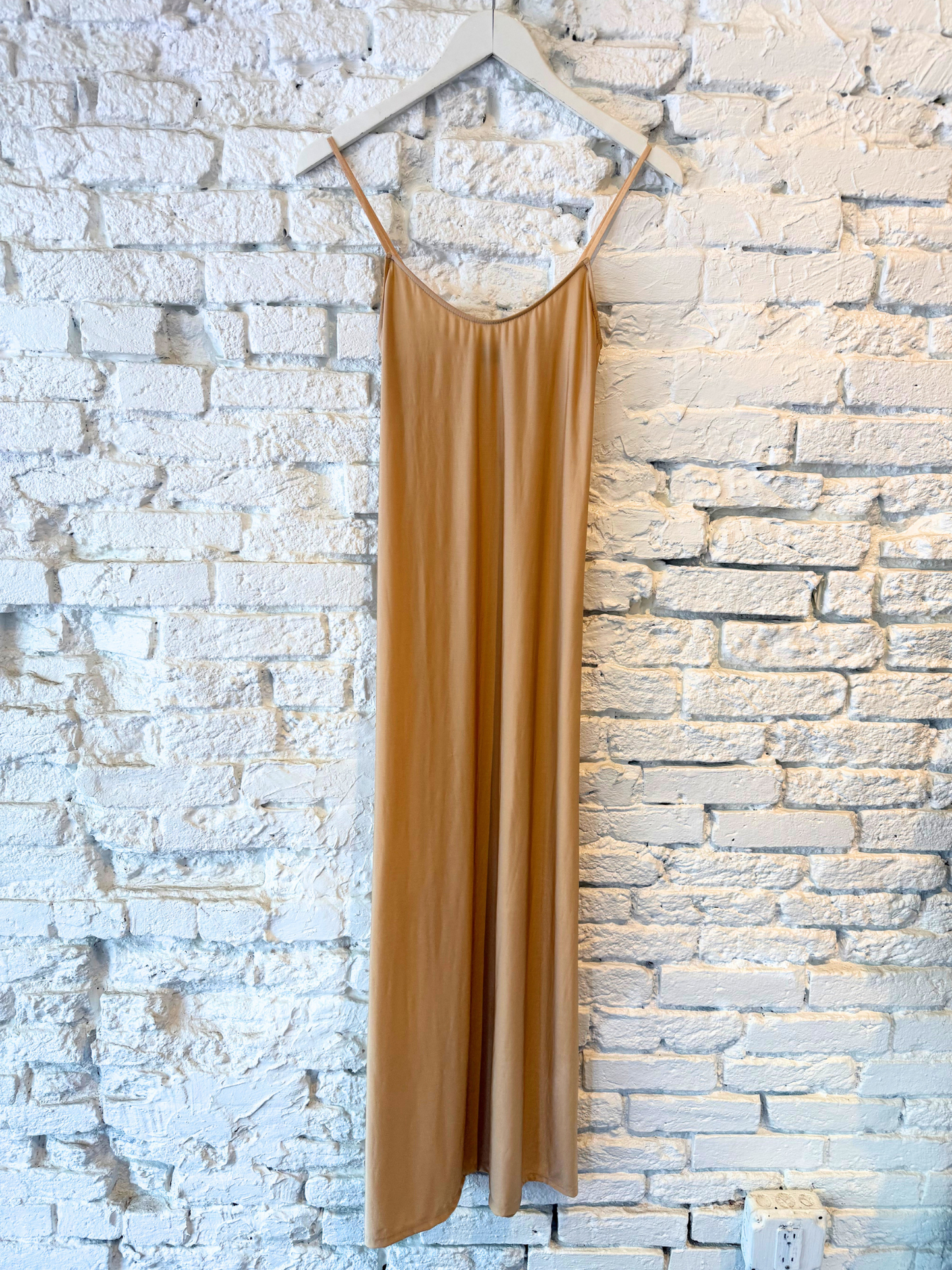Brown slip dress hanging against a stone wall