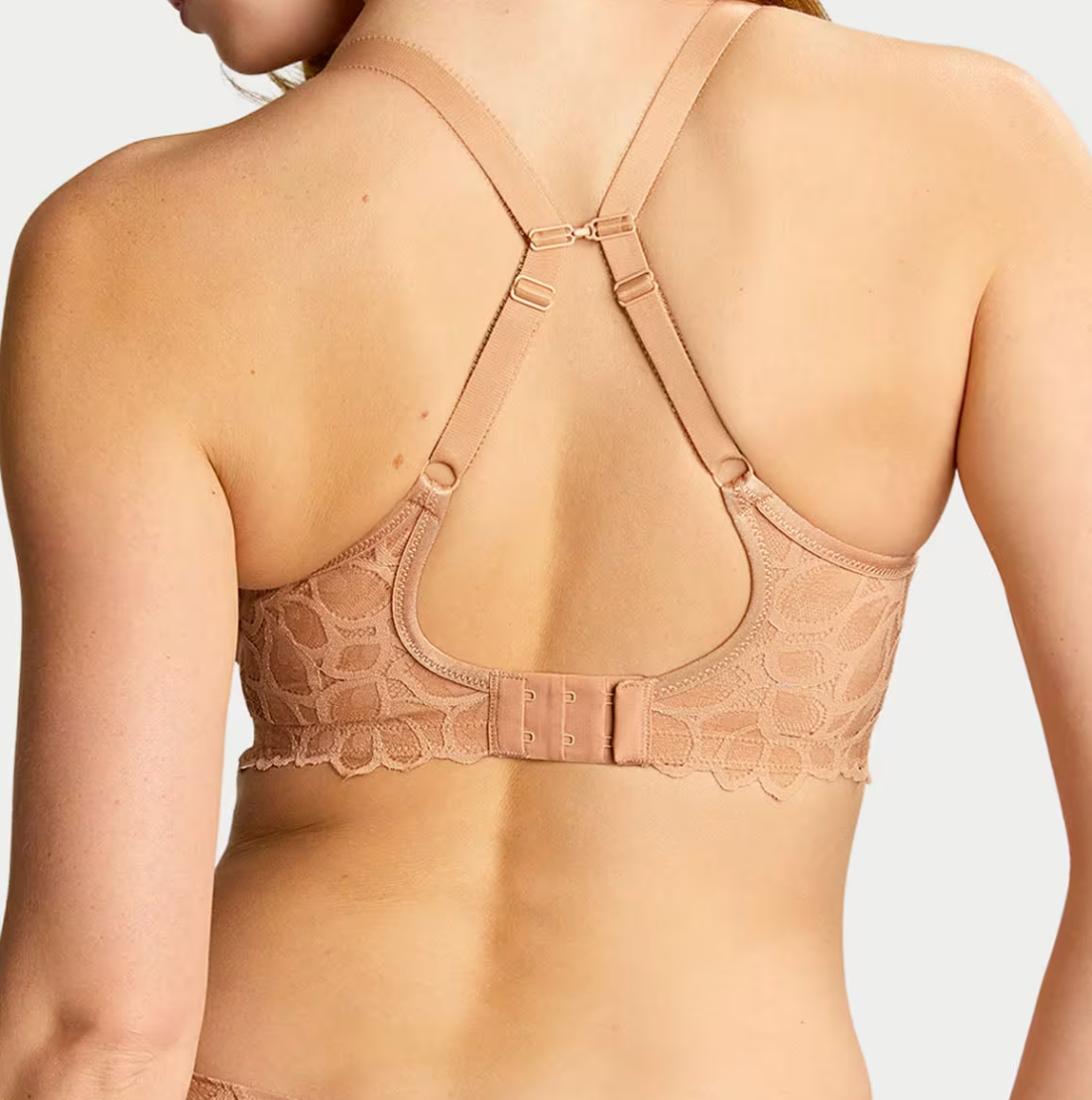 back of person wearing beige lace bra with straps making a j-hook.