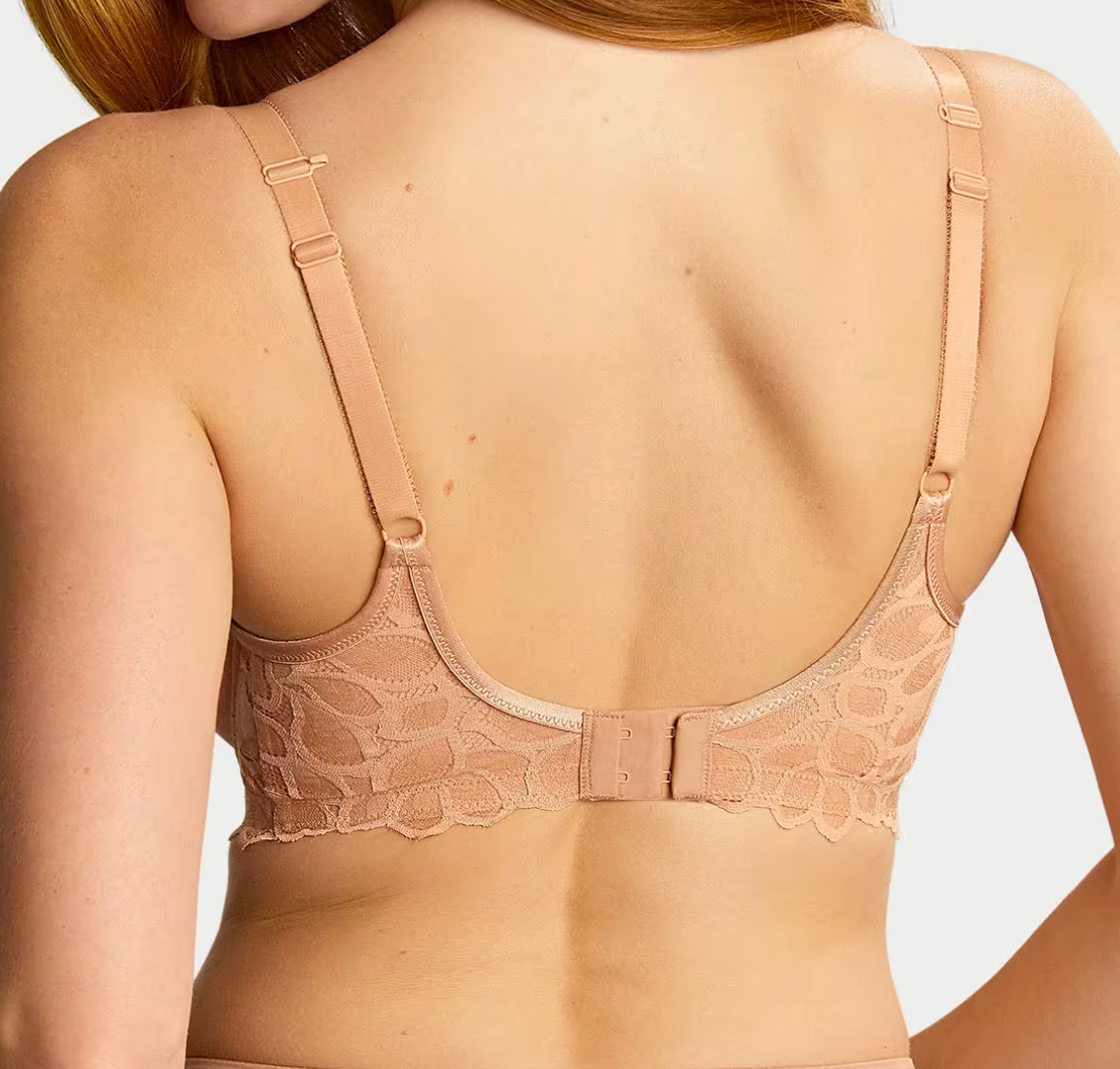 back of person wearing a beige lace bra against a white background.