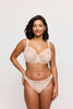 Model wearing light beige lace underwire bra and matching underwear in front of a white backdrop. 