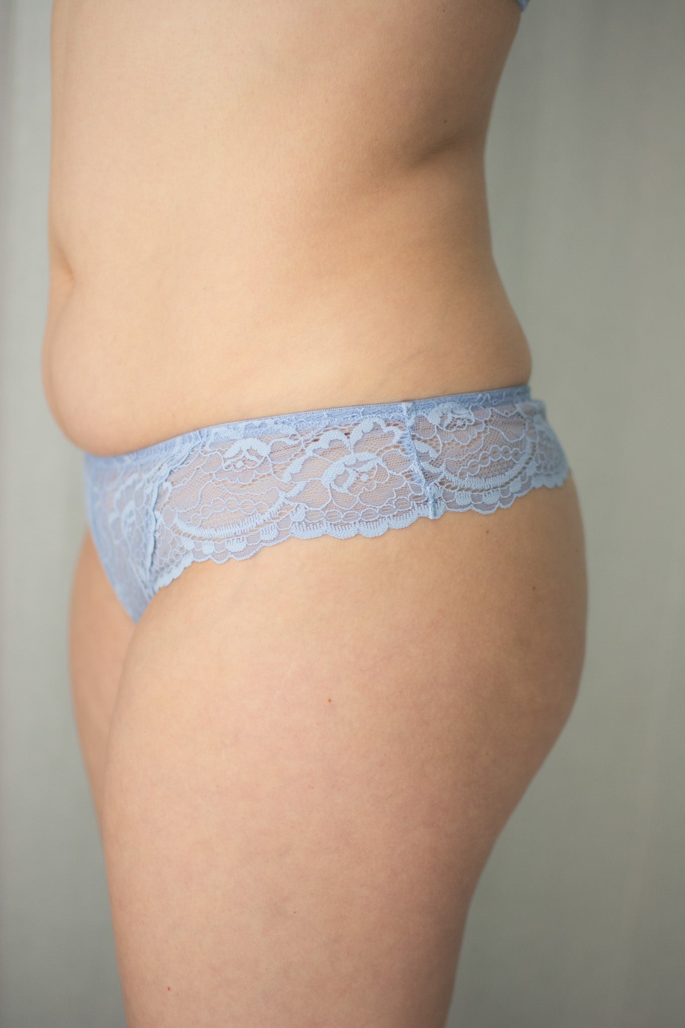 Light blue lace underwear worn by a person on a neutral background