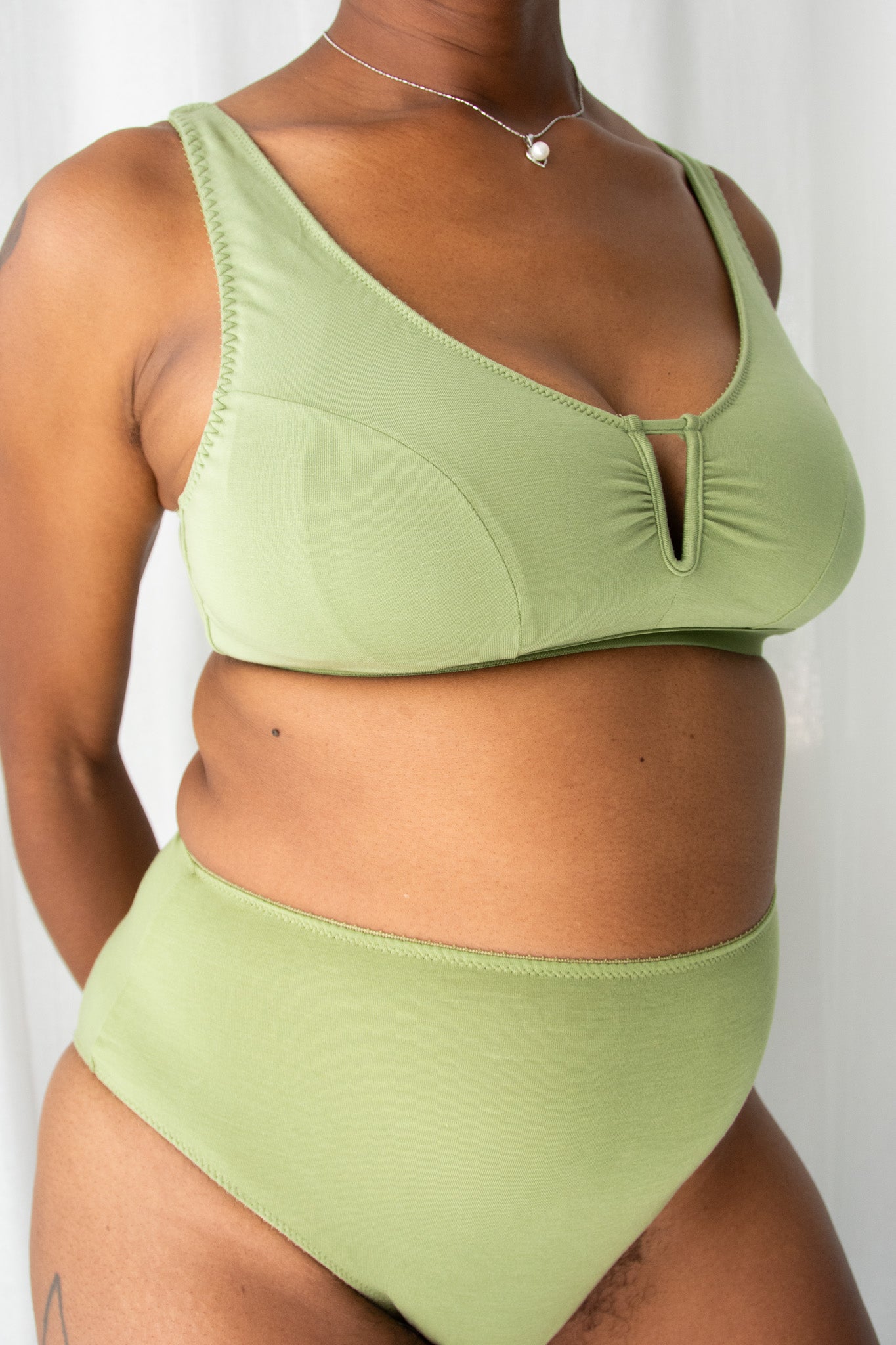 Green bra and underwear on body against white background.