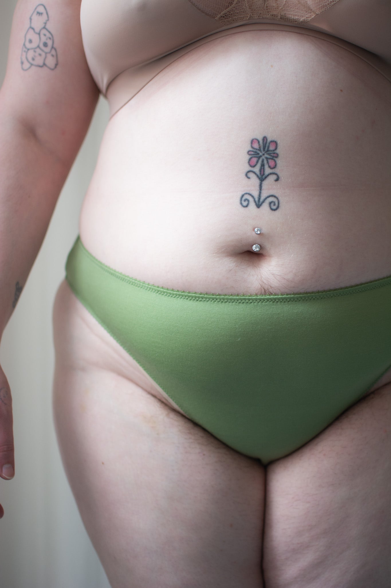 Person wearing green underwear against a neutral background.