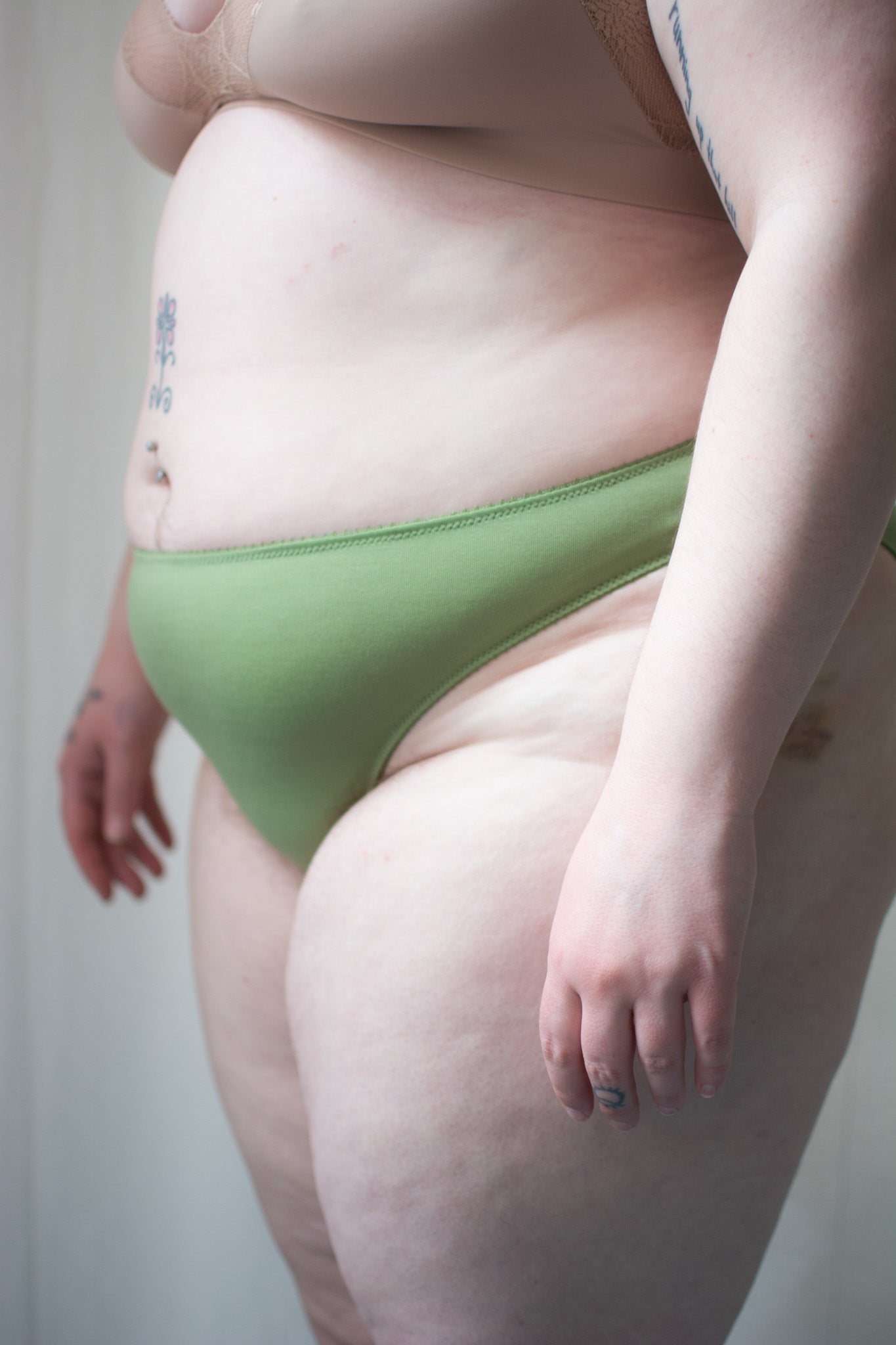 Person wearing green underwear against a neutral background.
