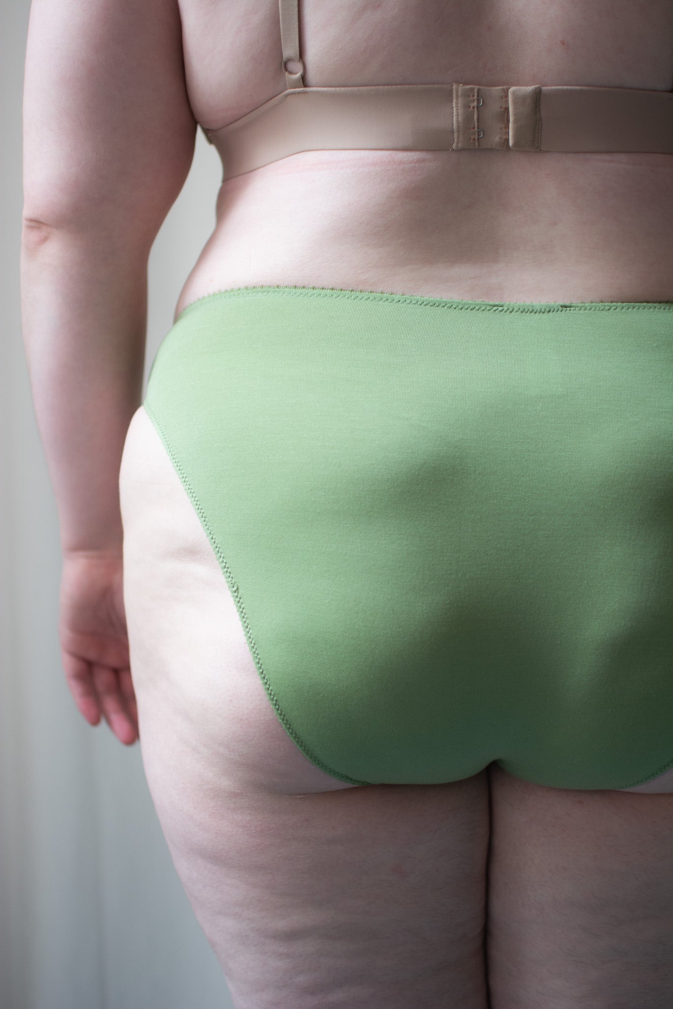 Person wearing green underwear against a neutral background.