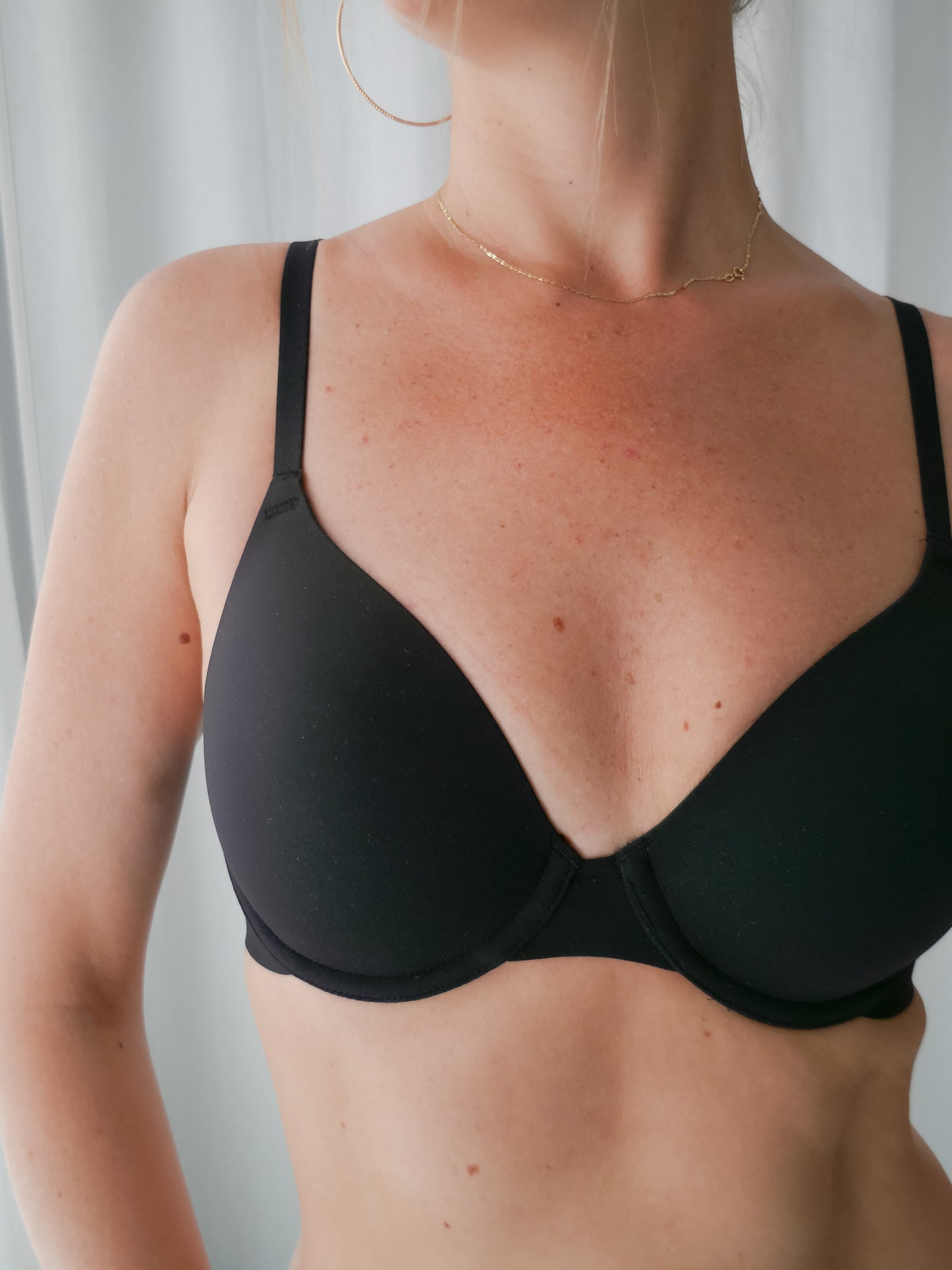 Person wearing a black bra against a neutral background