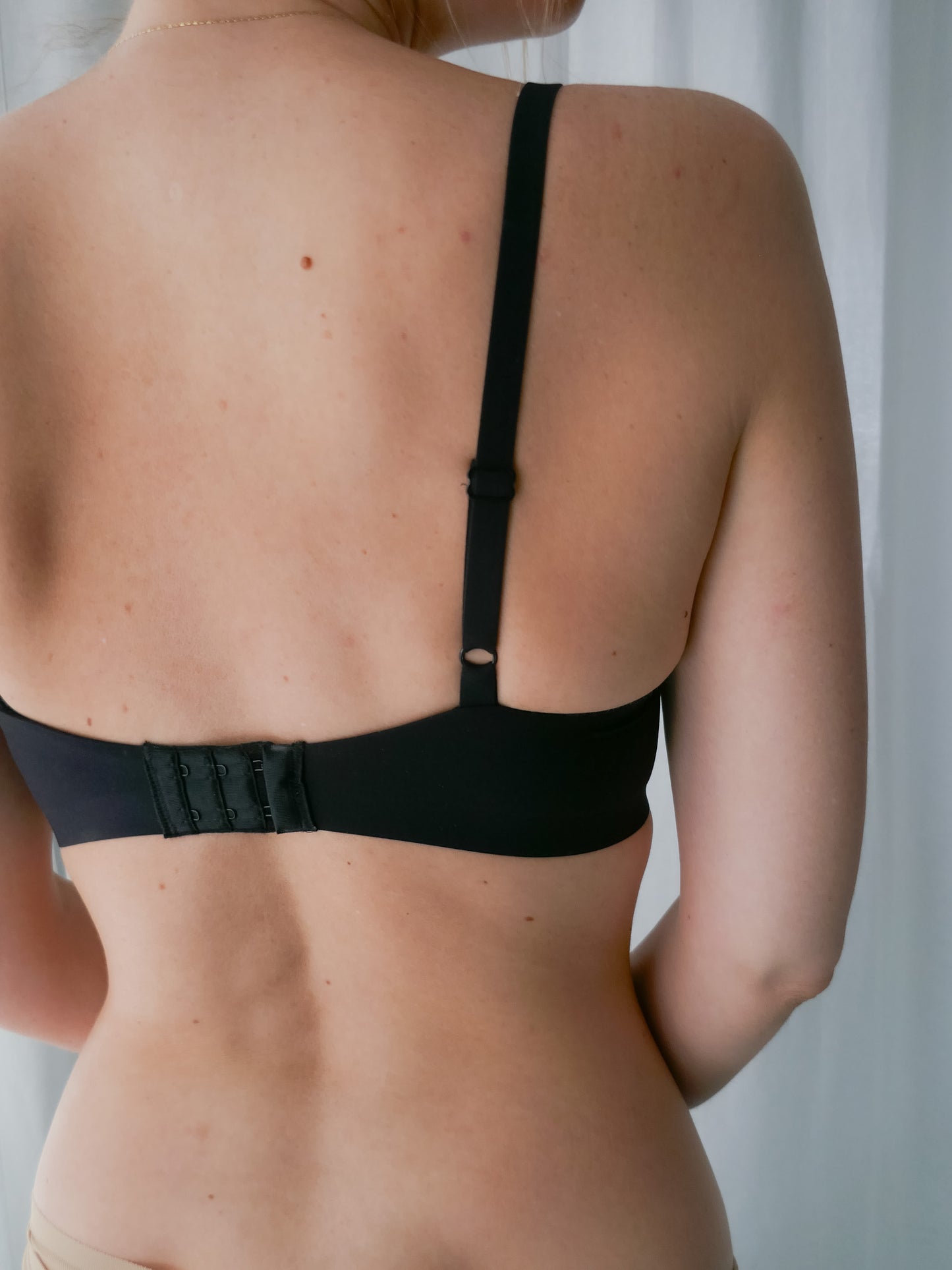 Person wearing a black bra against a neutral background