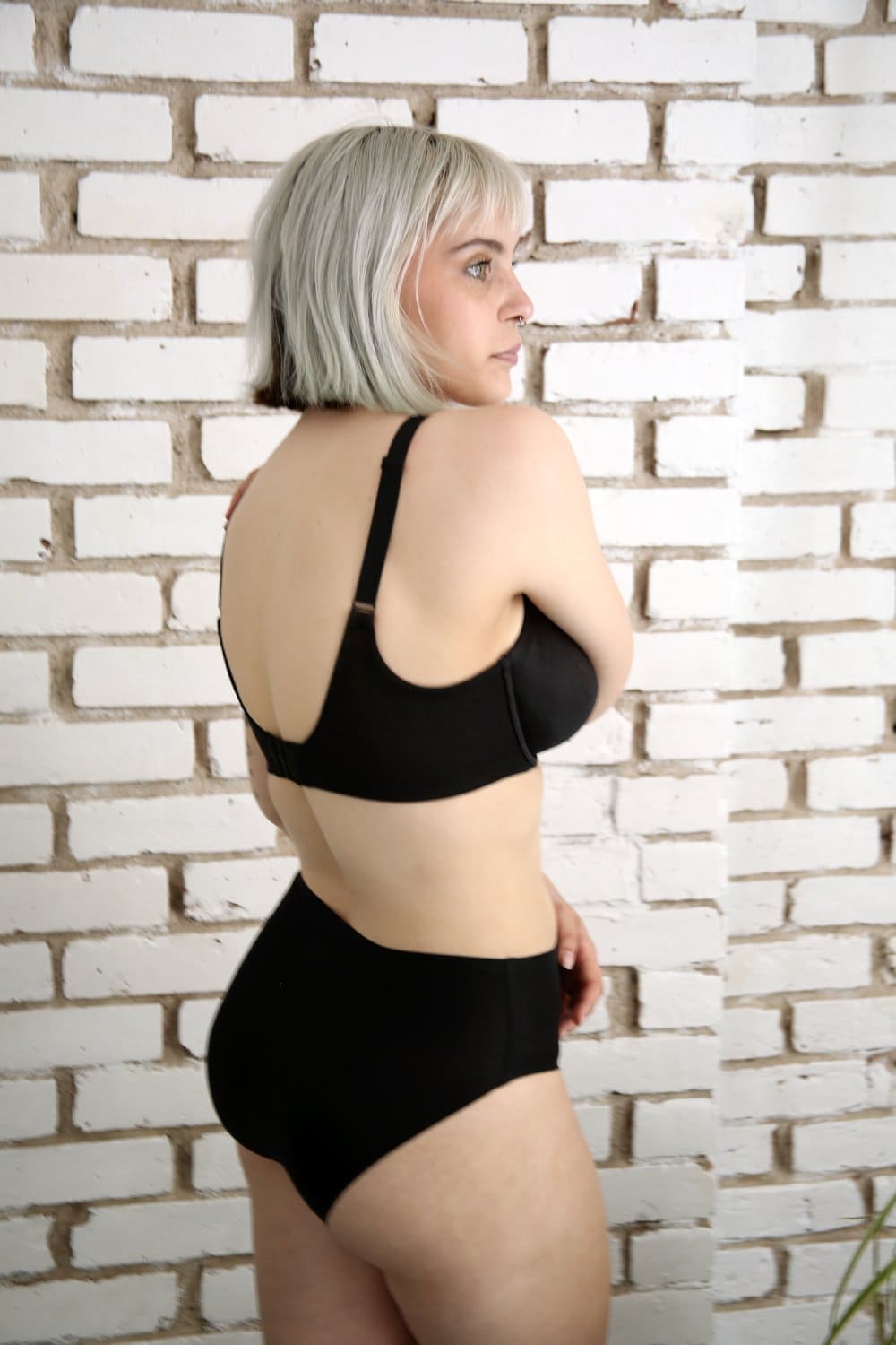 Wacoal Back Appeal full cup bra in black, back-side view on a model against a brick wall.