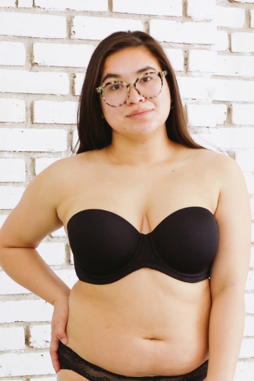 Wacoal red carpet strapless bra in black, front full-length view on a model against a brick wall.
