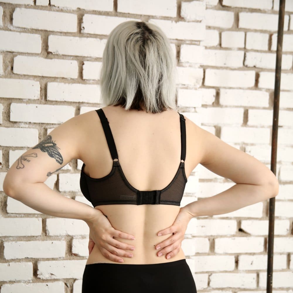 Wacoal Visual Effects Minimizer bra in black, back full-length view on a model against a brick wall.