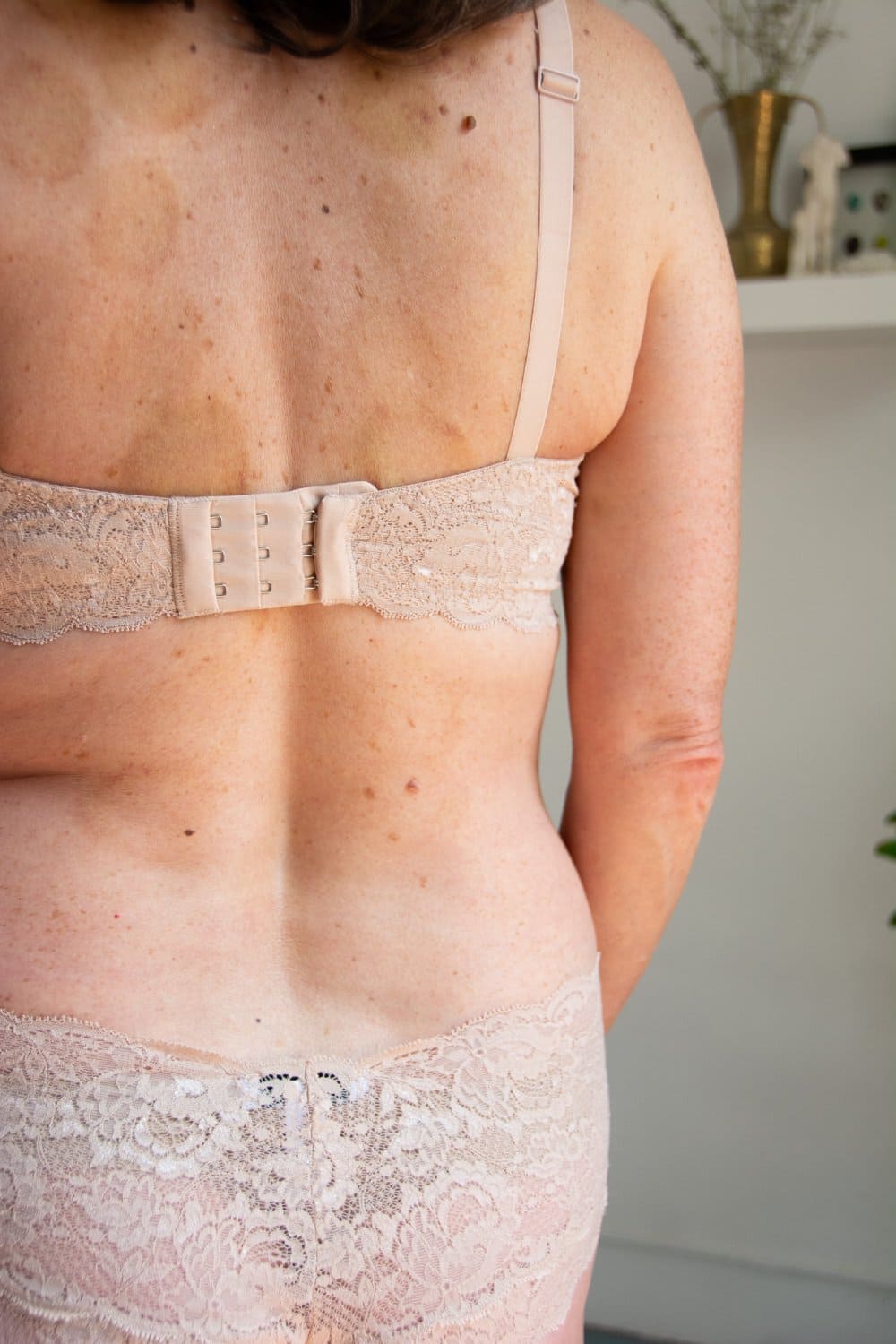 back of a person wearing a beige lace lingerie set