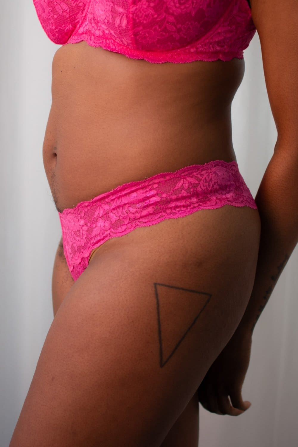 Person wearing bright pink lace underwear against a plain background