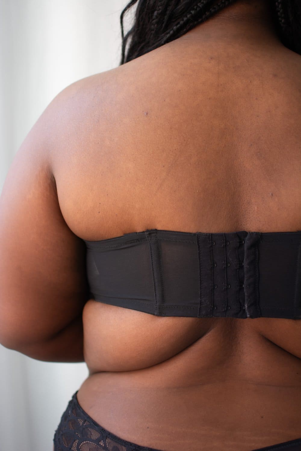 Elomi smooth underwire moulded strapless bra in black, back view on a model, close-up.